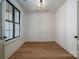 A minimalist room with wood floors and white walls, featuring a single window and a door that leads to another room at 229 Golf Course Rd, Maiden, NC 28650