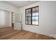 A minimalist room with wood floors and dark trimmed window. Features view of a white front porch and glass-paneled door at 229 Golf Course Rd, Maiden, NC 28650