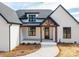 A close-up of the front porch, featuring a beautiful wooden door, exposed dark wood beams, and white brick at 229 Golf Course Rd, Maiden, NC 28650