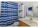 Cozy bathroom features blue and white striped shower curtain, storage shelves, and a wood vanity at 2512 Holly Oak Ln, Gastonia, NC 28056