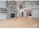 Open floor plan features a stone fireplace, wood floors, and view of the upper-level balcony at 6630 Vesuvius Furnace Rd # 1, Denver, NC 28037