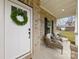 Welcoming front porch features brick accents, cozy seating, and a charming white door with a wreath at 5319 Carden Dr, Charlotte, NC 28227