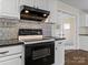 Close-up of kitchen with black appliances, stylish range hood and backsplash, and bright white cabinets at 105 Victoria Dr, Statesville, NC 28625