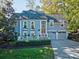 Charming two-story home featuring blue siding, mature trees and a two-car garage with a well manicured lawn at 94 Heritage Dr, Lake Wylie, SC 29710