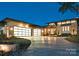 Striking exterior of a modern home with a curved driveway, stone accents, and stylish garage doors at dusk at 109 Twiggs Ln, Mooresville, NC 28117