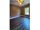 Spacious bedroom with dark brown walls, ceiling fan, and dark laminate flooring at 1703 Polk St, Monroe, NC 28110