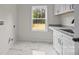 Bright laundry room with marble-look tile flooring, granite counters, and a view of the back yard at 315 Bonaventure Dr, Salisbury, NC 28147