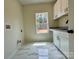 This well-lit laundry room features white cabinets, a sink, modern countertops, and elegant marble floors at 315 Bonaventure Dr, Salisbury, NC 28147