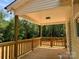 View of the covered porch with wooden railing and floor, perfect for enjoying the peaceful, wooded setting at 315 Bonaventure Dr, Salisbury, NC 28147