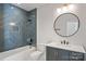 Modern bathroom with a herringbone tile shower, a round mirror and gray vanity at 705 Mcalway Rd, Charlotte, NC 28211