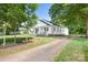 Cozy white home with black accents and a long driveway nestled among mature trees at 2401 Boy Scout Rd, Lincolnton, NC 28092