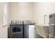 A tidy laundry room features a washer, dryer, utility sink and hot water heater for modern convenience at 2401 Boy Scout Rd, Lincolnton, NC 28092