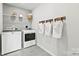 Well-lit laundry room with modern washer and dryer, storage shelves and wall hooks at 2565 Blue Sky Meadows Dr, Monroe, NC 28110