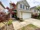 View of the home's exterior, featuring a two-car garage, lovely landscaping, and a walkway leading to the front door at 1096 Mountain Laurel Ct, Matthews, NC 28104