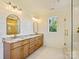 Bathroom featuring double vanities, a window for natural light, and a glass shower door at 4539 Polk Ford Rd, Stanfield, NC 28163