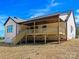 Exterior shot of a home featuring a covered back porch and wooden stairs, set against a bright blue sky at 4539 Polk Ford Rd, Stanfield, NC 28163