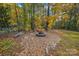 Tranquil backyard fire pit surrounded by colorful trees, rocks, and natural seating at 6003 Hawk View Rd, Waxhaw, NC 28173