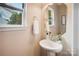 Elegant powder room with pedestal sink, classic mirror, and natural light from the window at 6003 Hawk View Rd, Waxhaw, NC 28173