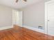 This bedroom offers hardwood floors, neutral paint and has a view out to the hallway with staircase railing at 1411 Lineberger Ave, Gastonia, NC 28052