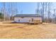 Bright single-story home featuring a wooden deck in a large, bare backyard, surrounded by a wooded area at 1162 Scenic Cir, Shelby, NC 28150