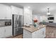 Bright kitchen with an island, stainless steel refrigerator, and open access to the living room with a fireplace at 122 W Heart Pine Ln, Statesville, NC 28677