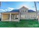 View of backyard, covered patio and the rear exterior of home with gray siding and black roof at 1865 Rock Hill Church Rd # 3, Matthews, NC 28104