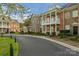 Elegant brick townhouses featuring charming balconies, complemented by mature landscaping and a curved street at 8336 Indigo Row, Charlotte, NC 28277