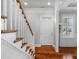 Bright foyer with hardwood floors, white staircase, and a white front door at 8336 Indigo Row, Charlotte, NC 28277