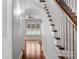 Bright hallway featuring hardwood floors, a staircase, and an archway leading to a room with a large window at 8336 Indigo Row, Charlotte, NC 28277