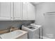 This laundry room features a utility sink, white cabinets and a washer and dryer at 8336 Indigo Row, Charlotte, NC 28277