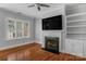 Bright living room features a fireplace, built-in shelving, hardwood floors and a ceiling fan at 8336 Indigo Row, Charlotte, NC 28277