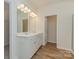 Bathroom has double sink vanity, bright mirror lights, and wood-look flooring at 1150 Red River Dr, Salisbury, NC 28144