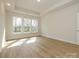 Airy bedroom with hardwood floors, tray ceiling, and multiple windows providing ample sunlight and views at 7169 Chamberlain Dr, Harrisburg, NC 28075