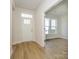 Bright entryway with hardwood floors, white door and trim, and a view into the adjacent room at 7169 Chamberlain Dr, Harrisburg, NC 28075