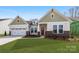 Inviting home showcasing a well-manicured lawn, a two-car garage, and attractive architectural details at 7169 Chamberlain Dr, Harrisburg, NC 28075
