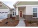 Inviting front porch with brick accents and craftsman-style door, offering a warm welcome to this lovely home at 7169 Chamberlain Dr, Harrisburg, NC 28075