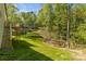 Exterior shot of the backyard's green lawn, wooden deck with stairs, and surrounding mature trees at 3146 Captains Cove Ln, Lincolnton, NC 28092