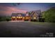 Stunning brick and stone home with three-car garage and warm exterior lighting at dusk at 3678 Rankin Rd, Concord, NC 28027
