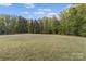 Large grassy lot surrounded by mature trees, offering a serene and private setting at 3678 Rankin Rd, Concord, NC 28027