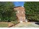 Exterior of a two-story brick home surrounded by mature trees and a gravel driveway at 115 Turner St, Lincolnton, NC 28092