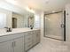 Bright bathroom features a double vanity, large mirror, and a glass-enclosed shower with marble tile at 145 Halite Way, Waxhaw, NC 28173