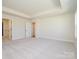 Spacious bedroom featuring tray ceilings, neutral walls, carpet flooring and doors to the bathroom and hallway at 145 Halite Way, Waxhaw, NC 28173