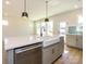 View of kitchen island with stainless steel dishwasher, farmhouse sink, and view of the backyard at 145 Halite Way, Waxhaw, NC 28173