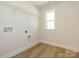 Well-lit laundry room with hardwood floors, wire shelving and washer/dryer hookups at 145 Halite Way, Waxhaw, NC 28173