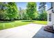 Backyard featuring a concrete patio, lush green lawn, mature trees, and partial fence at 107 Monterey Dr, Mooresville, NC 28117
