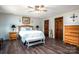Well-lit bedroom featuring wood floors, ceiling fan, white bedding, and dark wood doors and trim at 3092 Lee Lawing Rd, Lincolnton, NC 28092