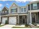 Attractive townhome featuring a stone facade, one-car garage, and manicured lawn at 6259 Tea Olive Dr # 178, Harrisburg, NC 28075