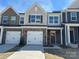 New two-story townhome showcasing a two-car garage, stone accents, and covered entryway at 6259 Tea Olive Dr # 178, Harrisburg, NC 28075