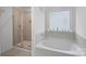 Bright bathroom featuring a walk-in shower and a separate soaking tub under a window at 7618 Fenn Way, Indian Land, SC 29707