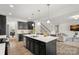 A modern kitchen featuring black cabinets, a white countertop island, and stainless steel appliances with hardwood floors at 7618 Fenn Way, Indian Land, SC 29707